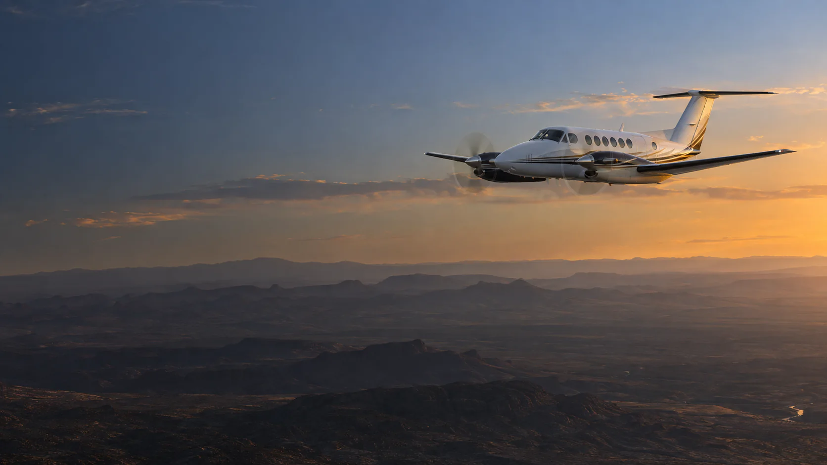 Twin-engine turboprop flying above the New Mexico high desert at last light.